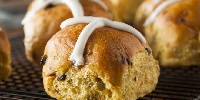 Close up of a few hot cross buns with frosted decorative cross on top.
